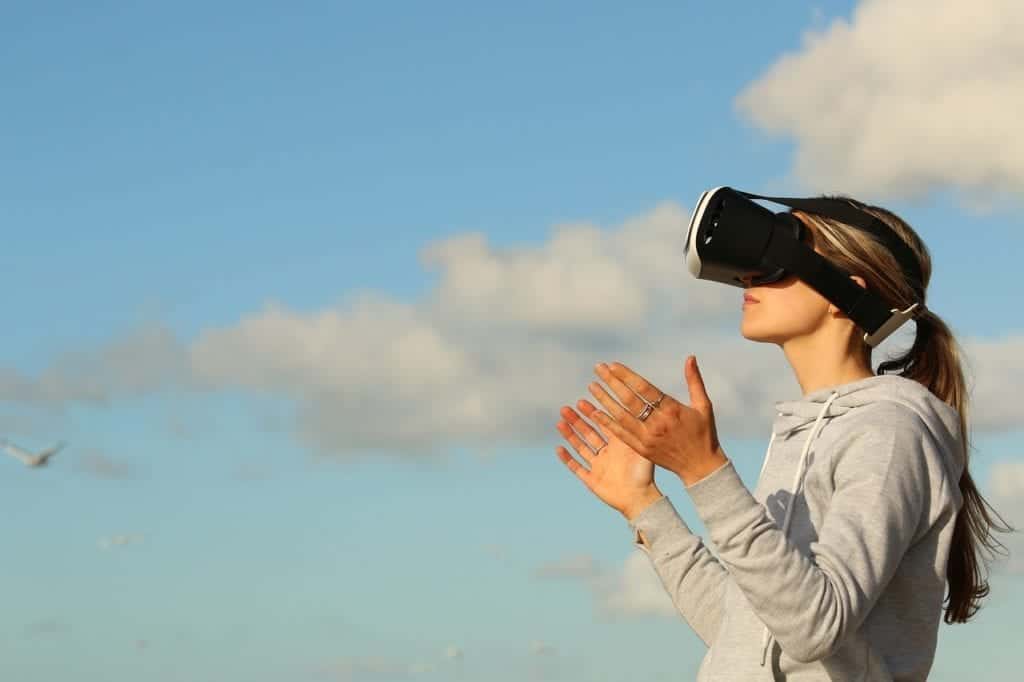 Woman standing outside using a virtual reality device to play a game