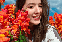 Photo of a smiling person among vibrant flowers