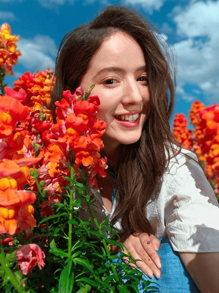 Photo of a smiling person among vibrant flowers